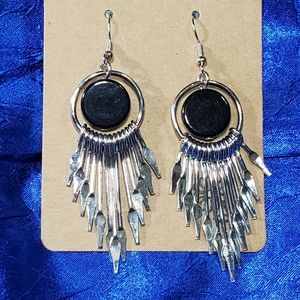 Black disc earrings with hanging daggers. Not sharp but pointy.